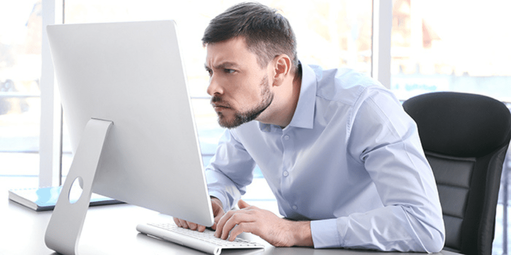 A man Leaning his neck out to look at his computer screen.