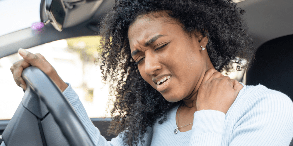 Women in drivers seat holding back of neck
